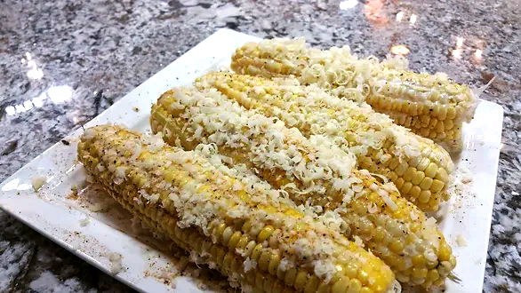 Ears of corn, seasoned with mayo, seasonings and cheese